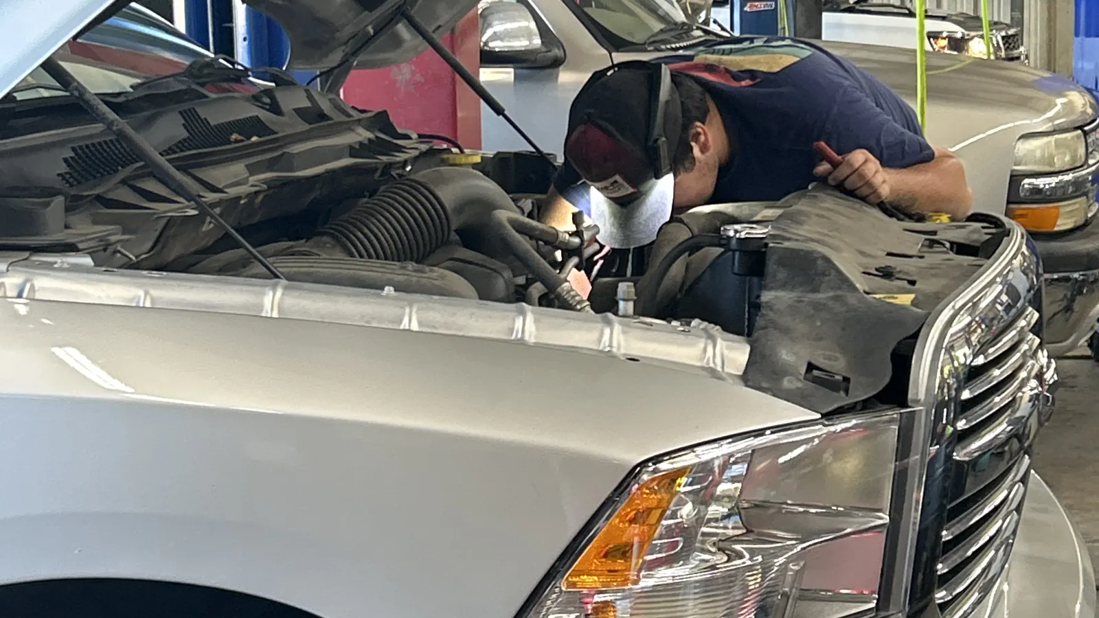 Technician working in the engine bay of a pickup at Gordon & Sandifer